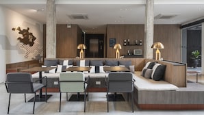 A spacious, modern living area with a high ceiling, a balcony, and a seating area with sofas and chairs. - Lilit Bang Lumphu Hotel (Bangkok)