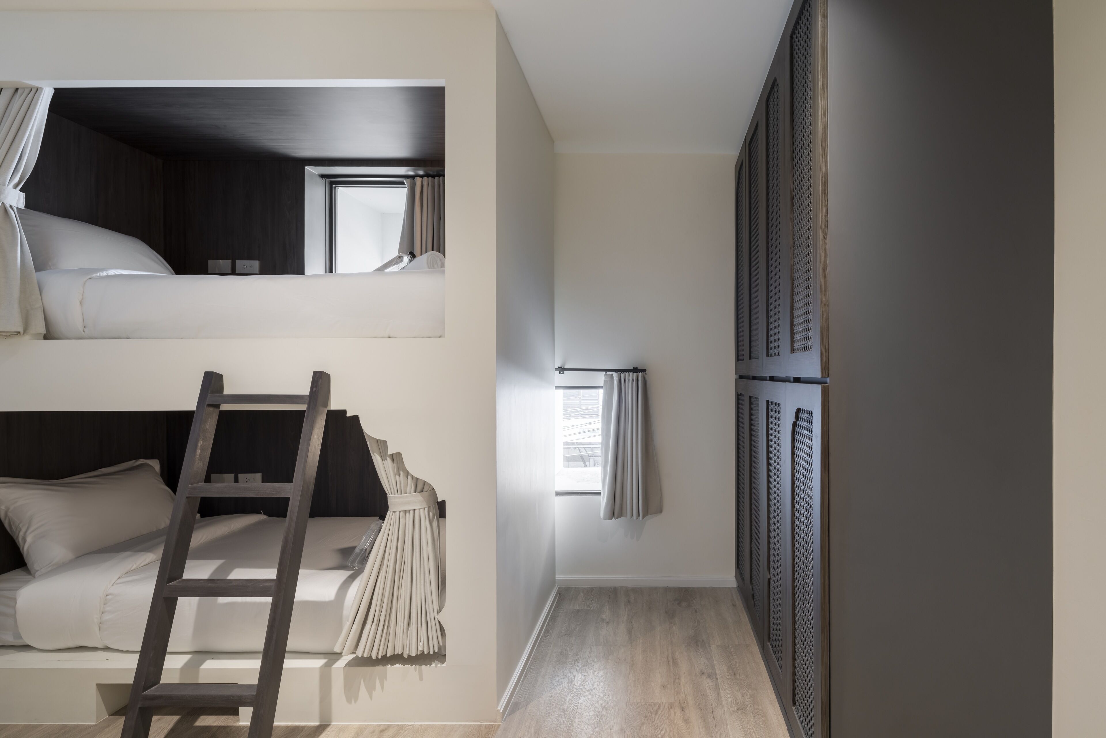 Una habitación con literas, una escalera y un ventanal con cortinas.