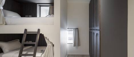 Una habitación con literas, una escalera y un ventanal con cortinas.
