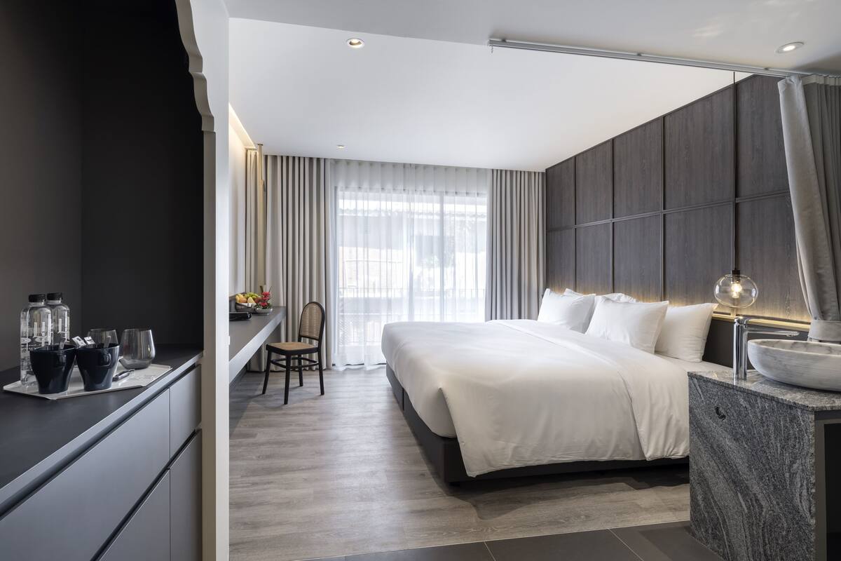 Una habitación de hotel moderna con una cama grande, un escritorio con una silla y un tocador con espejo.