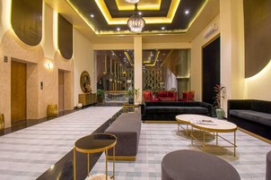 A spacious lobby with a central seating area, a patterned floor, and a modern chandelier.