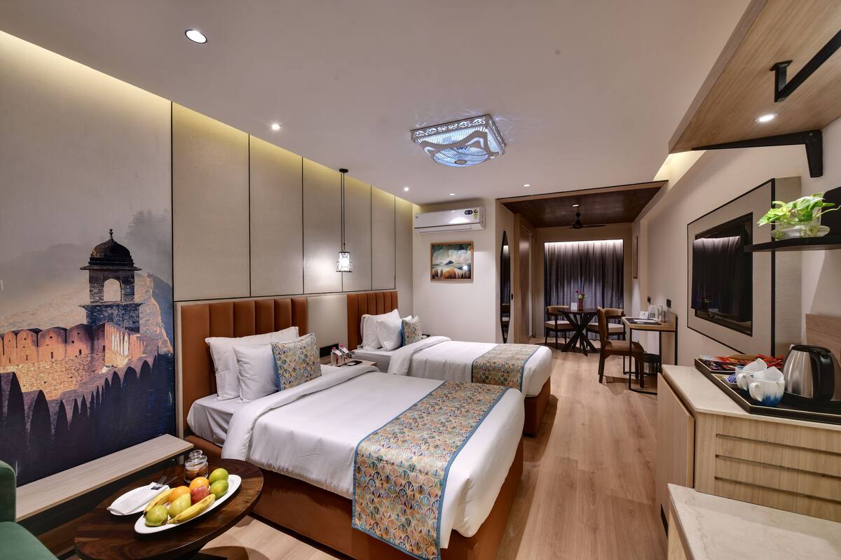 A hotel room with two beds, a dining area, and a TV.