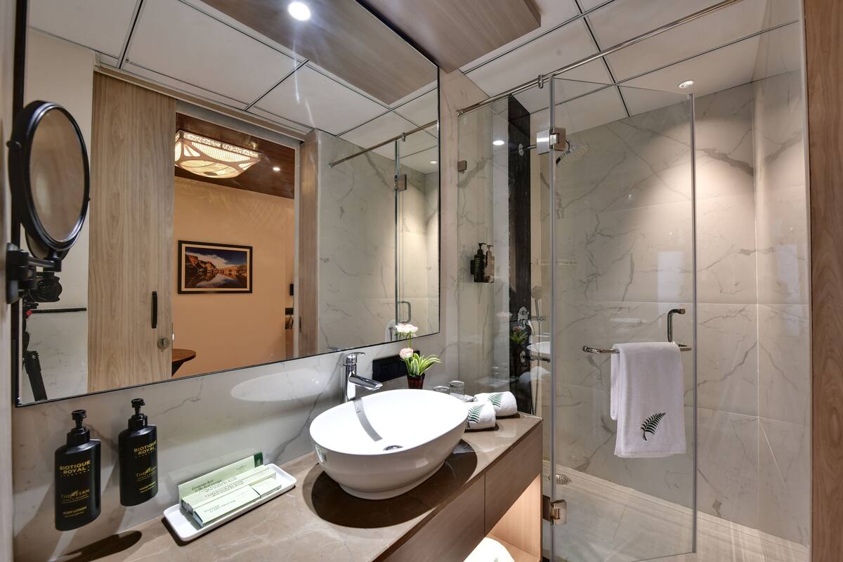 A modern bathroom with a large mirror, a round sink, and a glass-enclosed shower.