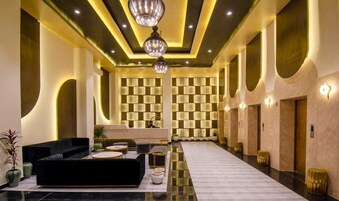 A modern lobby with a black sofa, a reception desk, and a patterned wall.