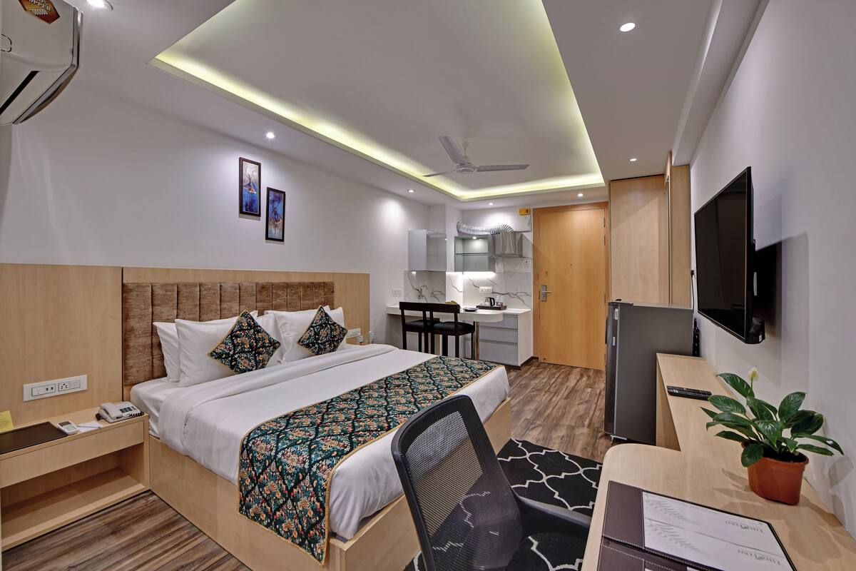 A modern hotel room with a bed, desk, chair, and a television.
