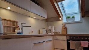 A modern kitchen with a built-in oven, a coffee maker, and a window above the sink.