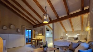 A cozy, well-lit room with a wooden ceiling, a sofa, a bed, and a dining area with a table and chairs.