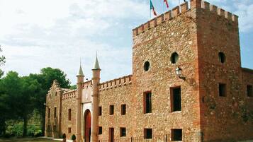Un bâtiment historique en pierre, doté d’une tour centrale, de fenêtres en arc de cercle et d’un mât pour drapeau.