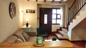 Ein Wohnzimmer mit Couchtisch aus Holz, einem grünen Teelicht, einer Uhr, einer Lampe und einer Treppe.