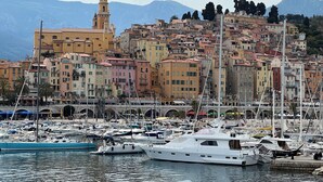 A marina with boats docked, a prominent tower, and colorful buildings in the background. - LE PAMELA facing the sea, exceptional view, private garden, private parking (Menton)