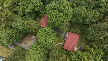 Vista aérea de um imóvel com um prédio de telhado vermelho, cercado por árvores verdes e densas.