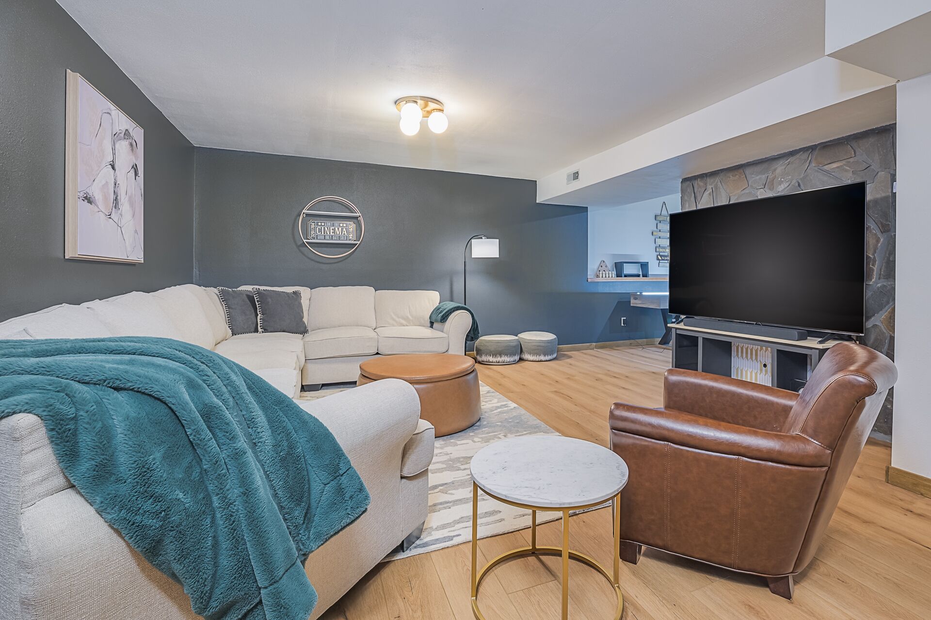 A modern living room with a sofa, armchair, coffee table, and a flat-screen TV.