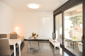 Una sala de estar moderna con sofá, mesa de comedor y televisor.