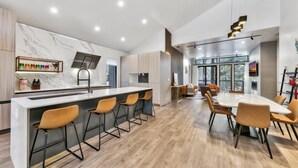 A modern kitchen with a marble backsplash, wooden flooring, and a central island with bar stools.