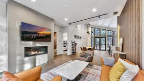 A modern living room with a fireplace, a large window, and a cozy seating area.