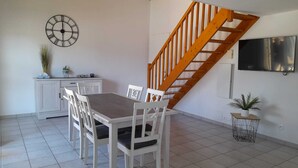 Un comedor con una escalera de madera, un reloj y un televisor en la pared.