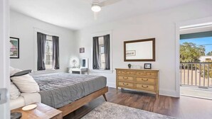 Une chambre à coucher comprenant un lit, une table de chevet, une commode et un ventilateur de plafond.