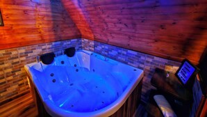 A wooden interior with a large bathtub, a tiled wall, and a digital control panel. - Hakuna Matata glamping (Monguí)