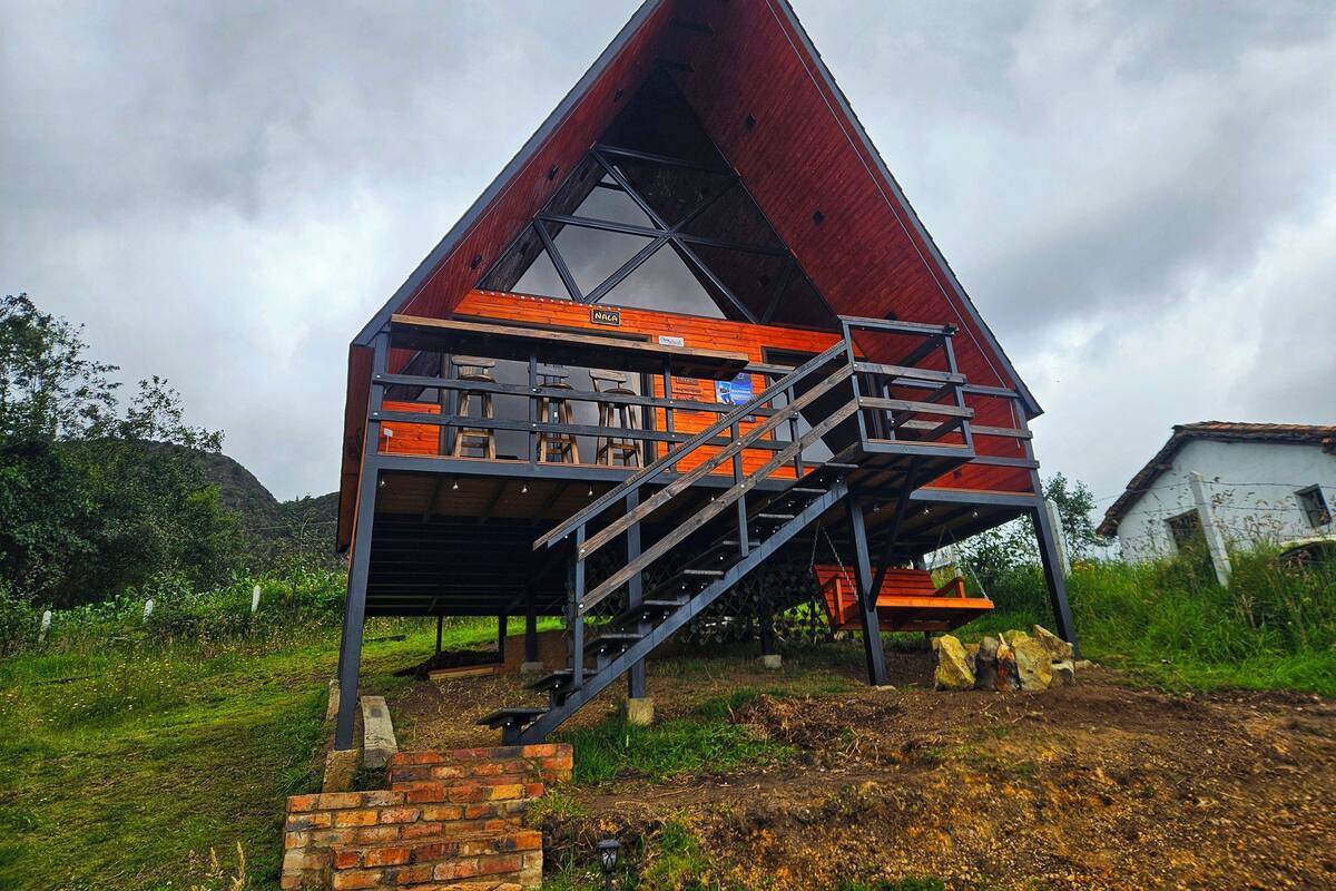 Un edificio triangular con un piso superior de madera y un piso inferior de ladrillo.