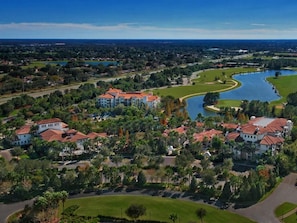 A golf course with a lake, surrounded by residential buildings with red roofs.