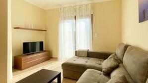 A living room with a flat-screen TV on a wooden cabinet, a beige sofa, and a coffee table. - Quiet and cozy villa near the beach (Denia)