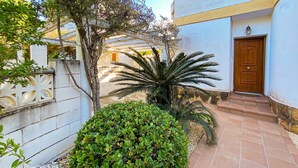 A courtyard with a palm tree, a wooden door, and a tiled pathway. - Quiet and cozy villa near the beach (Denia)