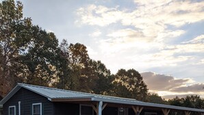 A rustic cabin with a porch, a small garden, and a gravel driveway. - Private cabin located on 7 acres in the country (Columbia)