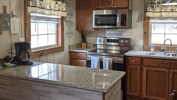 A kitchen with wooden cabinets, a granite countertop, a stainless steel oven, a microwave, and a coffee maker. - Private cabin located on 7 acres in the country (Columbia)