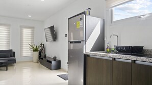 Una cocina moderna con refrigerador integrado, un lavamanos y un ventanal con vista al cielo.