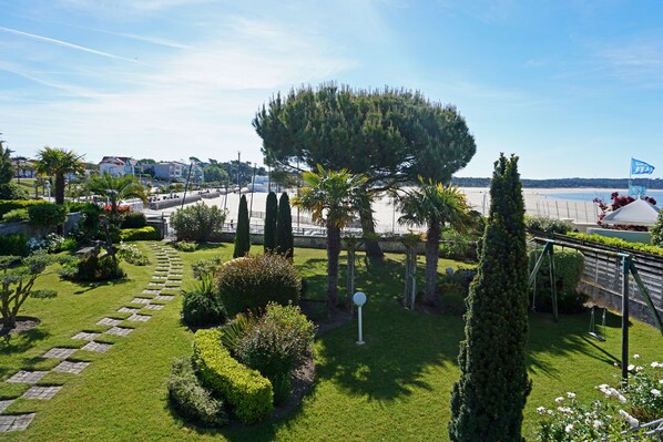 Um jardim bem cuidado, com um caminho, sebes bem aparadas e diversas árvores.