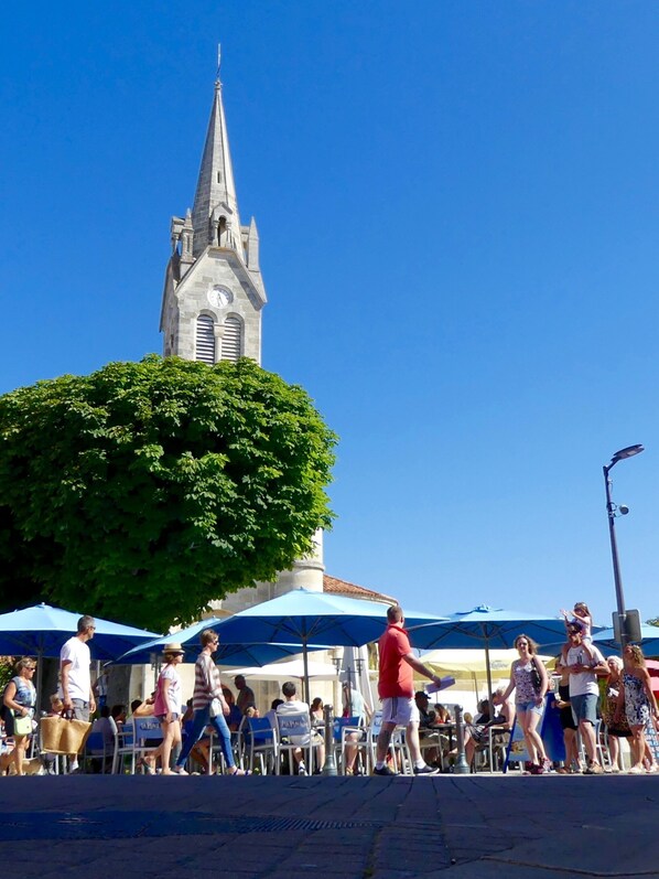 A public square with a church steeple in the background, surrounded by people and outdoor seating areas. - Excellent 4-person apartment with a view of the beach (Saint-georges-de-didonne)