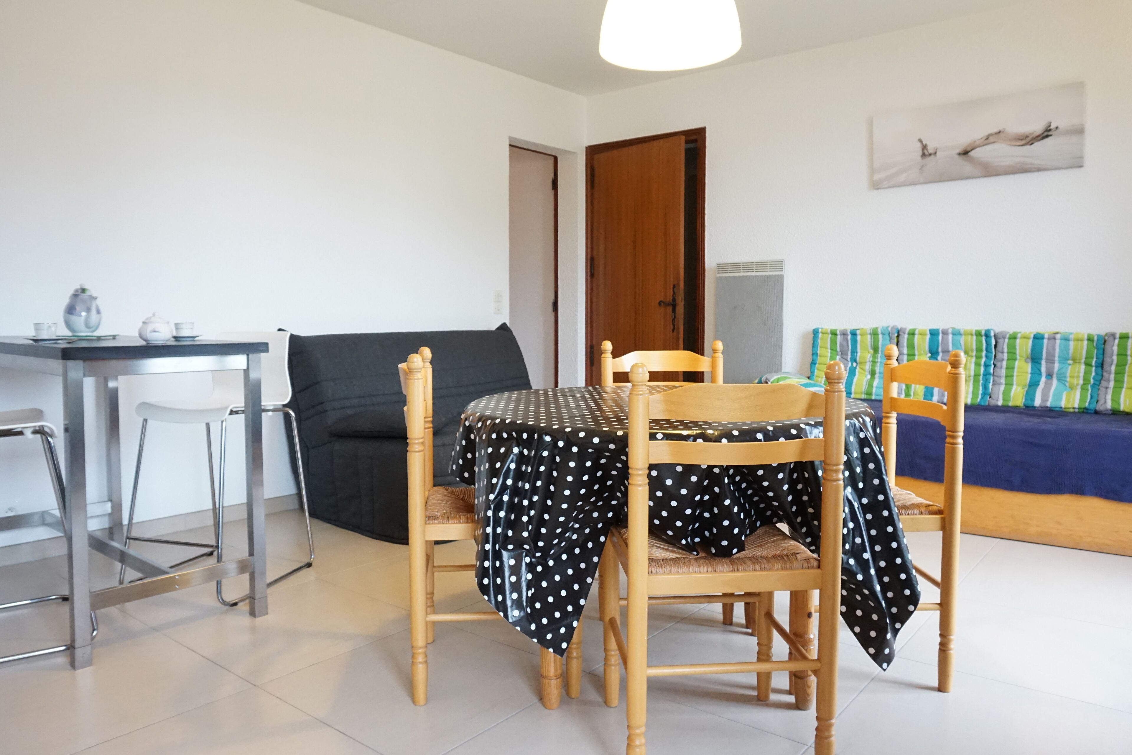 Una habitación pequeña y moderna con una mesa de comedor, dos sillas, un sofá y un televisor.