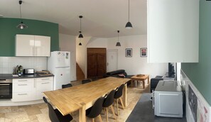 A compact kitchen with a wooden dining table, black chairs, and a refrigerator. - Beautiful Duplex Apartment (Espinchal)