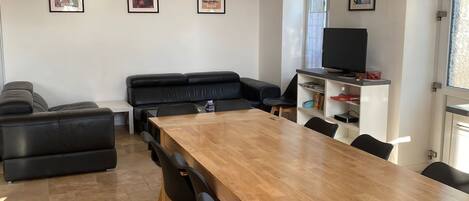 A modern dining area with a wooden table and black chairs, a black sofa, and pendant lighting.