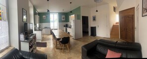A modern kitchen with a dining area, a black leather sofa, and a wooden door. - Beautiful Duplex Apartment (Espinchal)