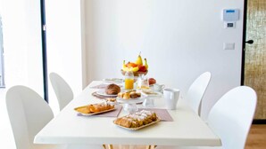Een ontbijttafel met diverse gerechten, een fruitschaal en een koffiepot.