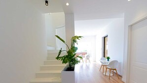 Een modern interieur met een trap, een eethoek en een plant.
