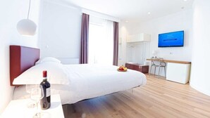 Een moderne hotelkamer met een groot bed, een bureau, een televisie en een ontbijtbalk.