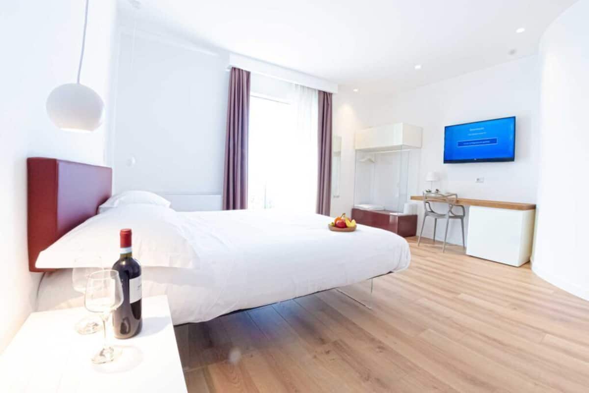 Ein modernes Hotelzimmer mit einem großen Bett, einem Schreibtisch, einem Fernseher und einer Frühstückstafel.