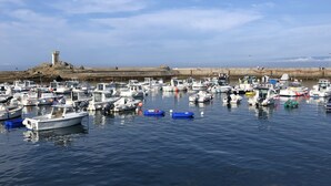 A marina with various boats docked, a lighthouse in the background, and a rocky shoreline. - Recently refurbished villa with sea views, closed garden and 80 m from beach. (Tregunc)