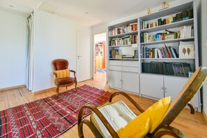 Una stanza con una libreria, un tappeto rosso decorato e una sedia di legno.