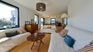A modern living room with a sofa, a coffee table, and a dining area. - Recently refurbished villa with sea views, closed garden and 80 m from beach. (Tregunc)