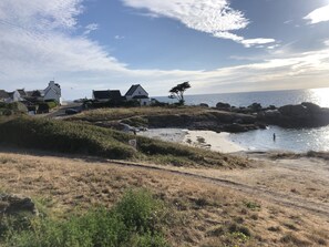 A coastal landscape with houses, a beach, and a rocky shoreline. - Recently refurbished villa with sea views, closed garden and 80 m from beach. (Tregunc)
