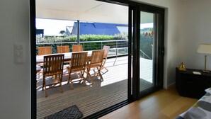A room with a sliding glass door leading to an outdoor deck with a table and chairs. - Recently refurbished villa with sea views, closed garden and 80 m from beach. (Tregunc)