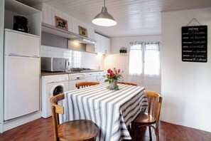 A kitchen with white cabinets, a microwave, a washing machine, and a dining table with chairs.