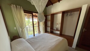 A bedroom with a large bed, a wooden wardrobe, and a balcony with curtains. - Bia Trixx's Home (Porto Seguro)
