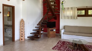 A living room with a wooden staircase, a television, a sofa, and a coffee table. - Bia Trixx's Home (Porto Seguro)