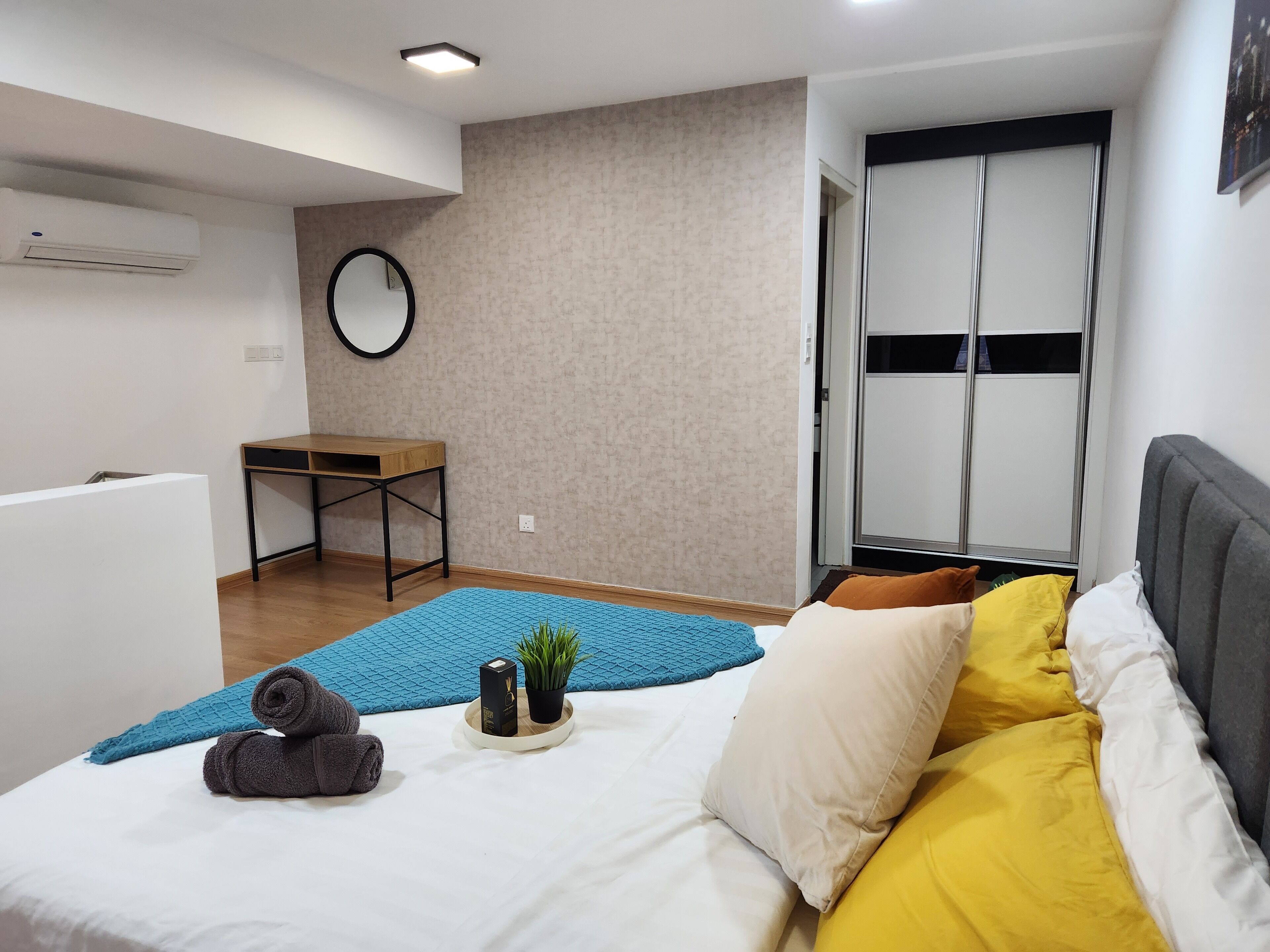 A modern bedroom with a bed, a small table, a mirror, and a wardrobe.