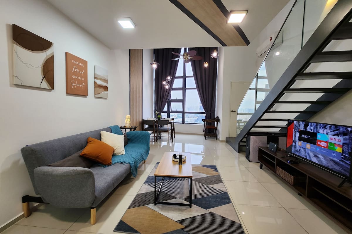 Una sala de estar moderna con un sofá, una mesa de centro y un televisor sobre un mueble.
