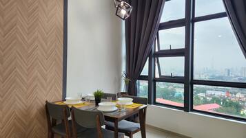 Un área de comedor con un ventanal grande, una pared con patrón de espiga y vistas a un paisaje urbano.